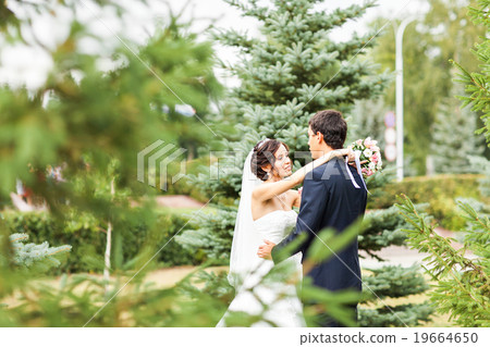 Young wedding couple walking together at park Young wedding couple walking together at park 19664650