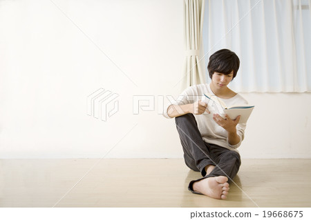 A young man sitting on the floor for reading 19668675