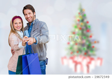 Composite image of smiling couple showing credit card and shoppi Composite image of smiling couple showing credit card and shoppi 19672349