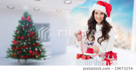 Composite image of smiling brunette in santa hat packing gifts Composite image of smiling brunette in santa hat packing gifts 19673254