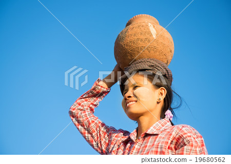 Young Asian traditional farmer carrying clay pot on head Young Asian traditional farmer carrying clay pot on head 19680562