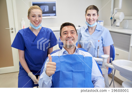 happy female dentists with man patient at clinic happy female dentists with man patient at clinic 19688001