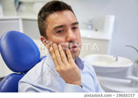 man having toothache and sitting on dental chair 19688157