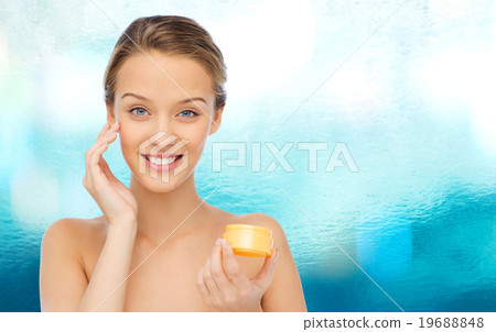 happy young woman applying cream to her face 19688848
