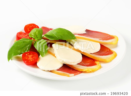 Sliced prosciutto and mozzarella with basil and tomatoes Sliced prosciutto and mozzarella with basil and tomatoes 19693420