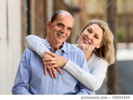 smiling mature woman hugging man while walking 19694304