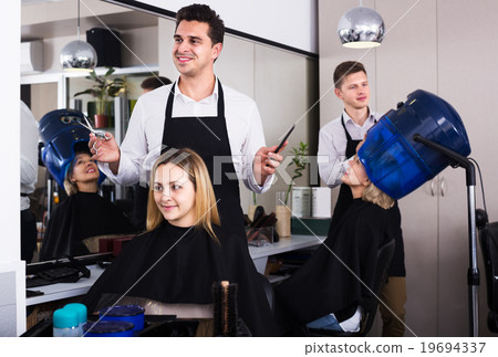 Hairdresser cuts hair at salon 19694337