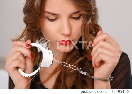 Appealing young girl posing with handcuffs.  19695450