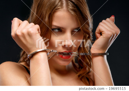 Sexual young woman is biting at handcuffs. 19695515