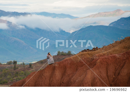 Woman sitting on big red sandstone rock formation Woman sitting on big red sandstone rock formation 19696982