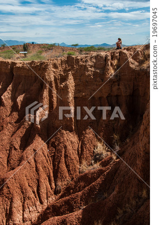 Blond young woman sitting on cliff of red 19697045