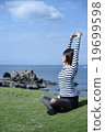 一位小姐坐有藍天和海背景的草坪 19699598