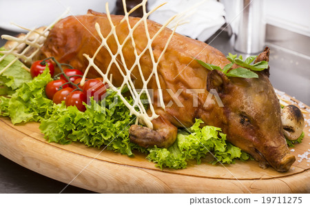 roasted suckling pig with vegetables on a wooden p roasted suckling pig with vegetables on a wooden p 19711275