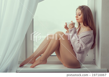 Girl sits on window and drink of the cup. 19718867