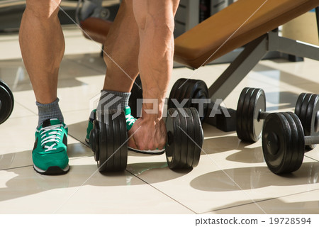 Bodybuilder picks up dumbbells. 19728594