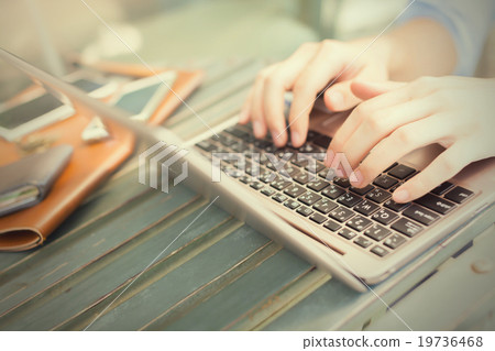 Hands typing on laptop and smart phone on his side Hands typing on laptop and smart phone on his side 19736468