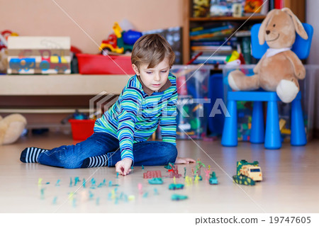 Kid boy playing with toy soldiers indoors at Kid boy playing with toy soldiers indoors at 19747605