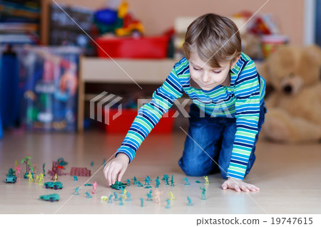 Kid boy playing with toy soldiers indoors at Kid boy playing with toy soldiers indoors at 19747615