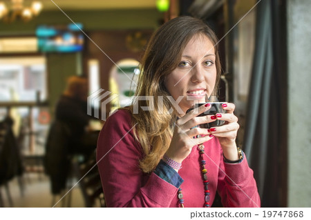 young brunette drinking coffee at a coffee shop young brunette drinking coffee at a coffee shop 19747868