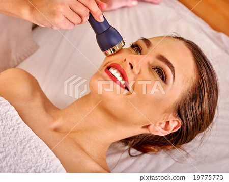 Young woman receiving electric facial massage. Young woman receiving electric facial massage. 19775773