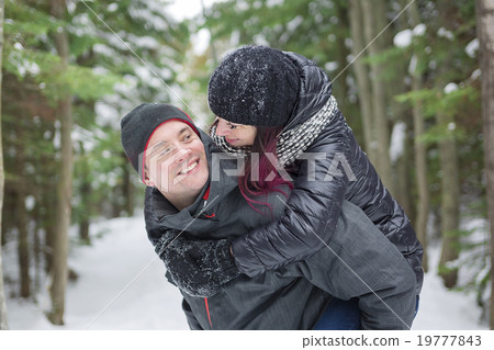 Winter couple piggyback in snow smiling happy and 19777843