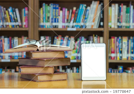 old book on the desk in library with tablet and glasses 19778647