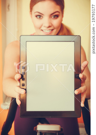 Woman on exercise bike holding pc tablet copyspace Woman on exercise bike holding pc tablet copyspace 19793177
