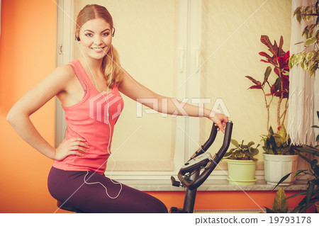 Woman on exercise bike listening music. Fitness Woman on exercise bike listening music. Fitness 19793178