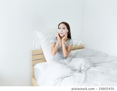 Woman doing facial mask on bed 19805450