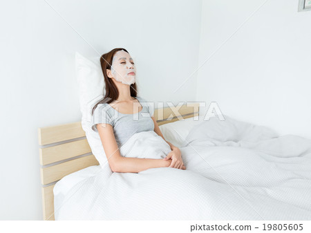 Asian woman using paper mask on face and lying down on the bed Asian woman using paper mask on face and lying down on the bed 19805605