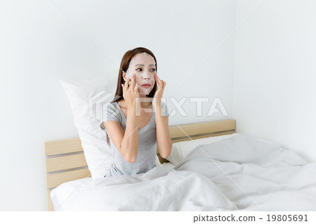 Woman using paper mask and sitting on bed 19805691