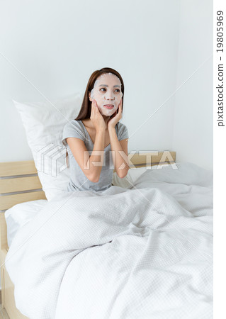 Asian woman using the paper mask and sitting on bed 19805969