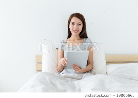 Woman sitting on bed and use of the digital tablet Woman sitting on bed and use of the digital tablet 19806663