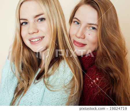 Two young girlfriends in winter sweaters indoors Two young girlfriends in winter sweaters indoors 19824719