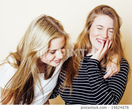 two blond teenage girl fooling around messing hair 19824876