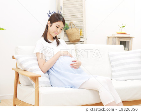 Pregnant woman sitting on the sofa and touching her stomach 19826350