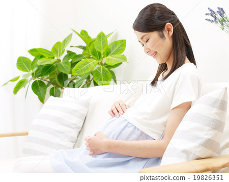 Pregnant woman sitting on the sofa and touching her stomach 19826351