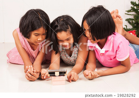 little asian girl watching movie on mobile phone in the room little asian girl watching movie on mobile phone in the room 19828292