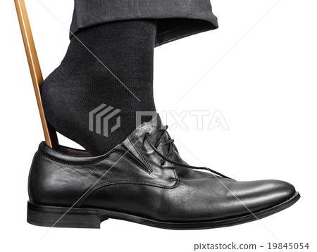man dons black shoe with shoehorn isolated man dons black shoe with shoehorn isolated 19845054
