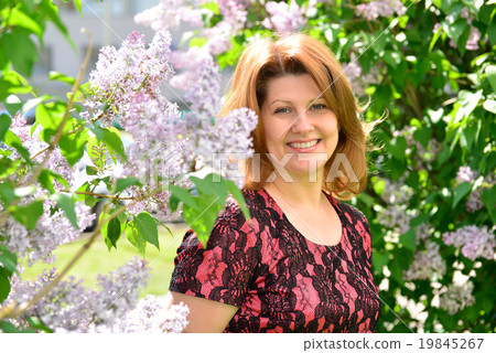 Middle-aged woman near blossoming lilac 19845267