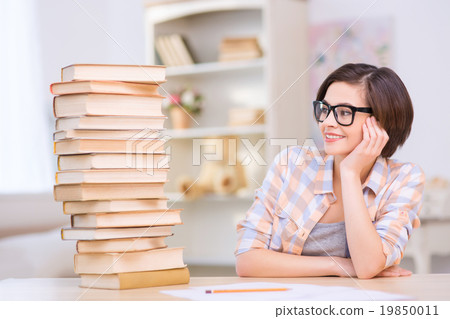 Young girl sitting in front near pile of books.  19850011