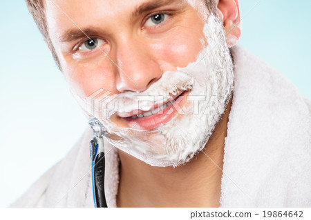 Young man shaving using razor with cream foam. Young man shaving using razor with cream foam. 19864642