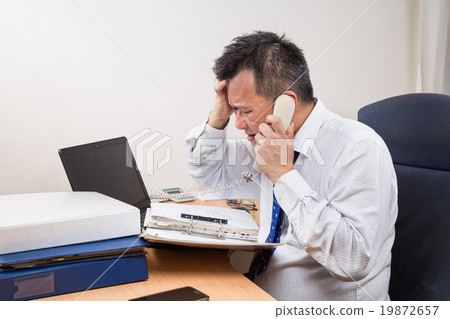 Stressful Asian manager talk on phone in office 19872657