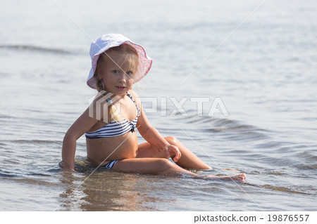 girl sits at the water's edge girl sits at the water's edge 19876557