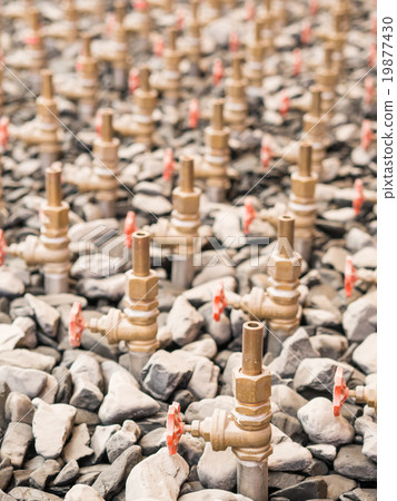 Water taps of fountain court, closeup among gravel. Stack of wat 19877430