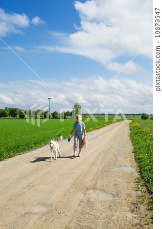 Woman with a dog goes on a country road 19879547