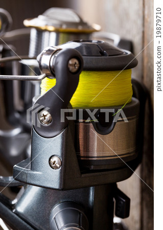 closeup fishing reel on wooden board background closeup fishing reel on wooden board background 19879710