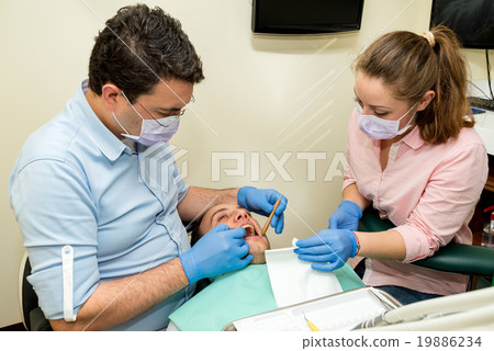 Dentist doing a dental treatment on a patient Dentist doing a dental treatment on a patient 19886234
