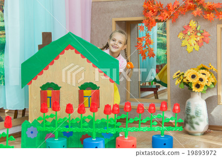 The girl looks out from behind the scenery a country house in the matinee in kindergarten 19893972