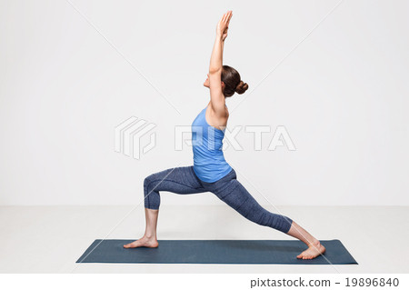 Woman practices yoga asana utthita Virabhadrasana 19896840